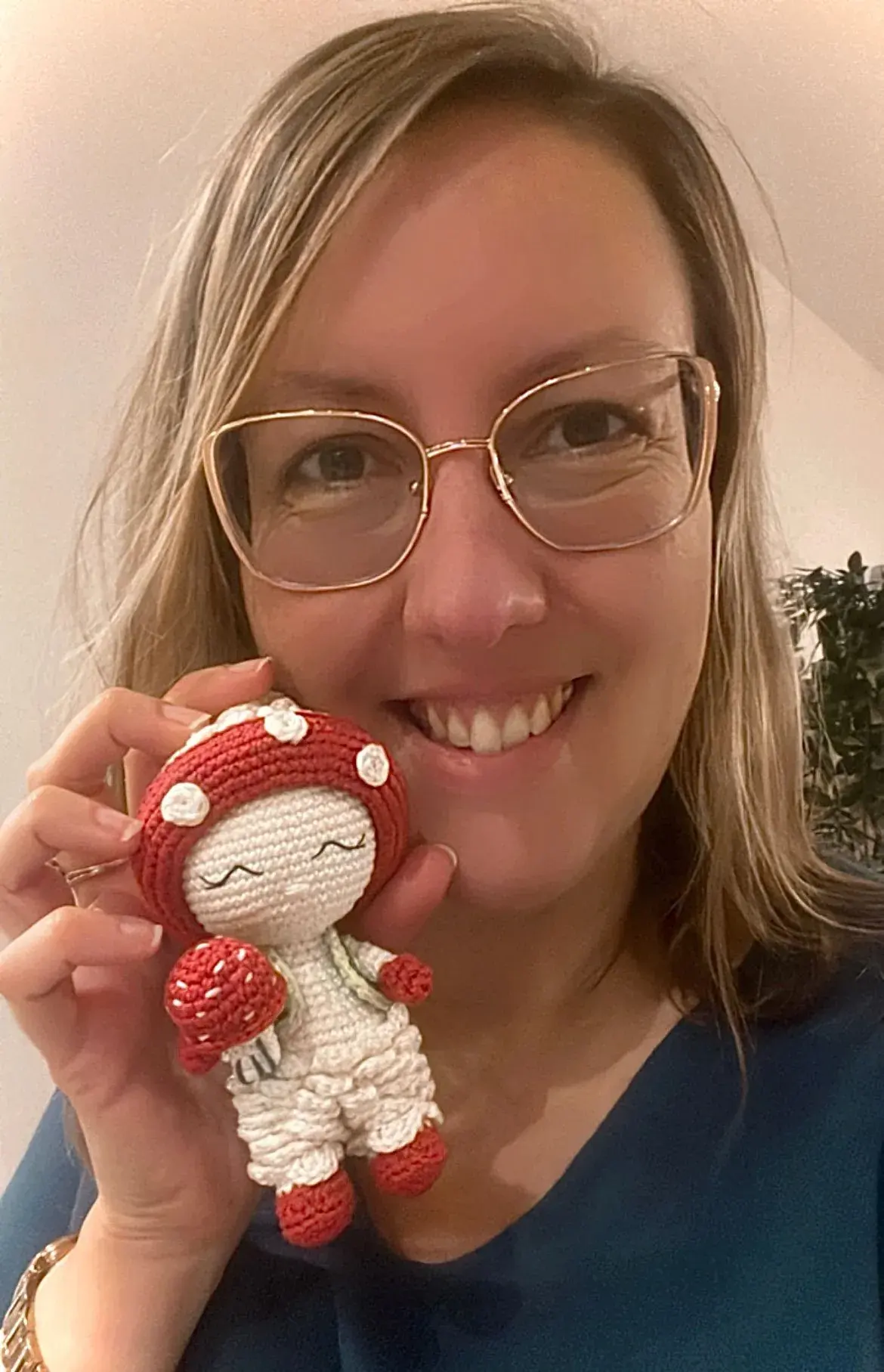 Valérie, sourire aux lèvres, tenant une petite poupée au crochet